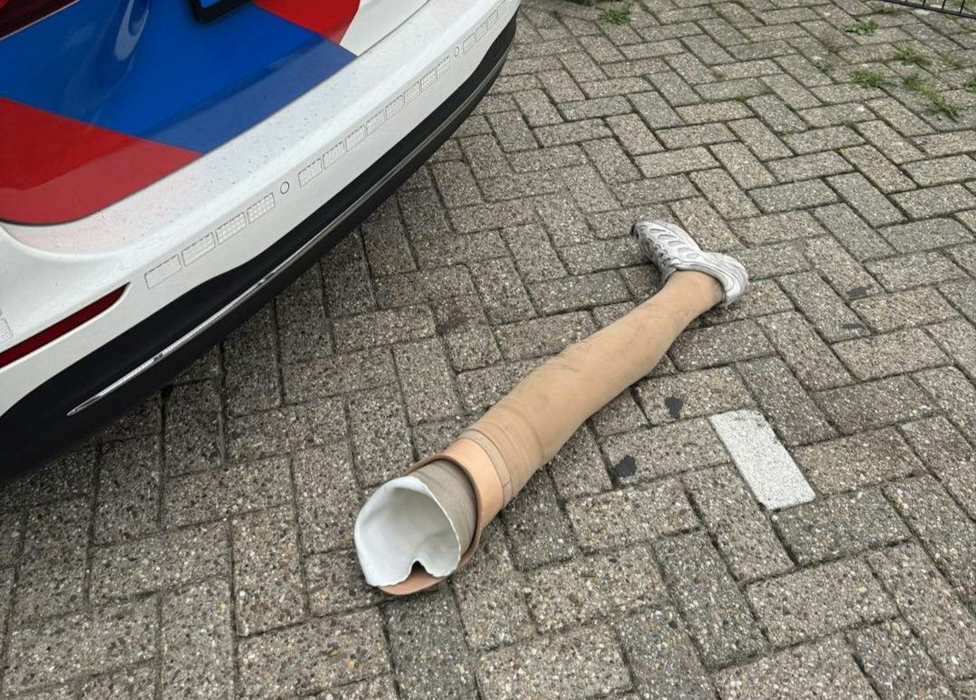 Das Bein eines mutmaßlichen Ladendiebs liegt vor einem Polizeiauto auf der Straße.