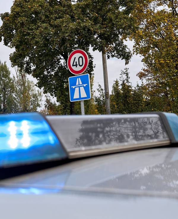 Ein Polizeifahrzeug mit Blaulicht ist neben einem Autobahnschild zu sehen (Symbolfoto)