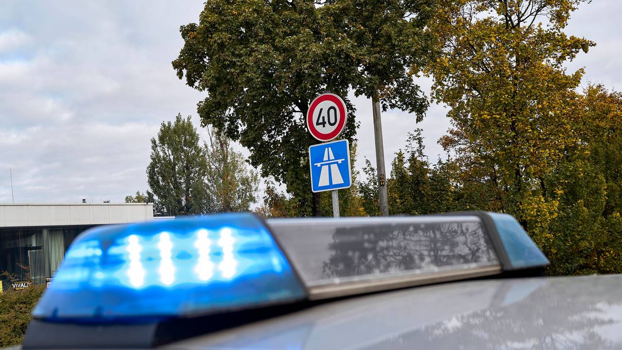 Ein Polizeifahrzeug mit Blaulicht ist neben einem Autobahnschild zu sehen (Symbolfoto)