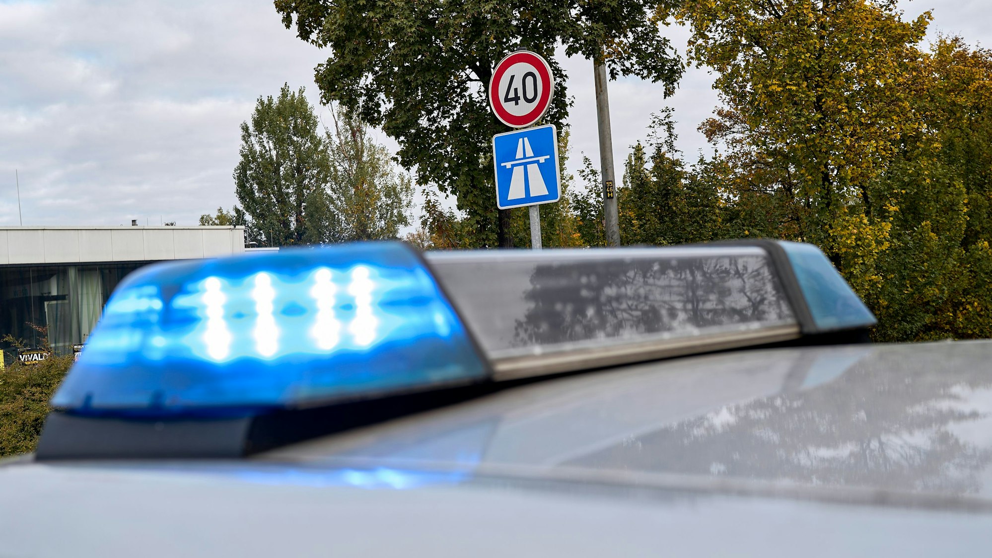 Ein Polizeifahrzeug mit Blaulicht ist neben einem Autobahnschild zu sehen (Symbolfoto)