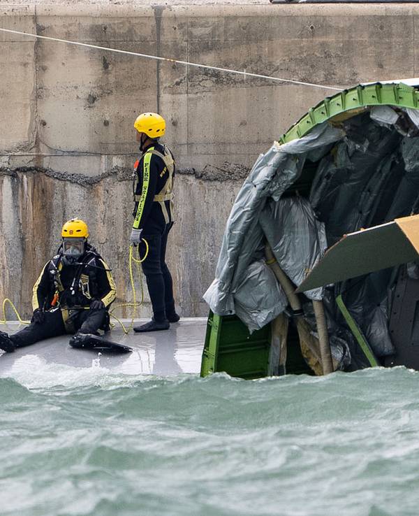 Ein Taucher bereitet sich auf die Inspektion des Frachtflugzeugs vor, das auf dem Flughafen in Hongkong von der Landebahn abgekommen ist und über die Piste hinaus ins Meer schlitterte.