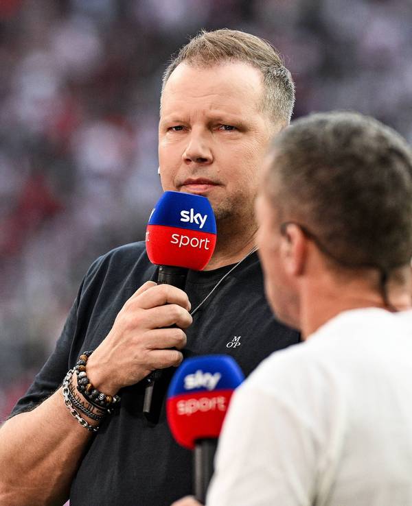Wolff Fuss hält ein Sky-Mikrofon vor seinen Mund und guckt streng.