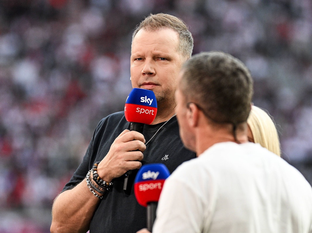 Wolff Fuss hält ein Sky-Mikrofon vor seinen Mund und guckt streng.