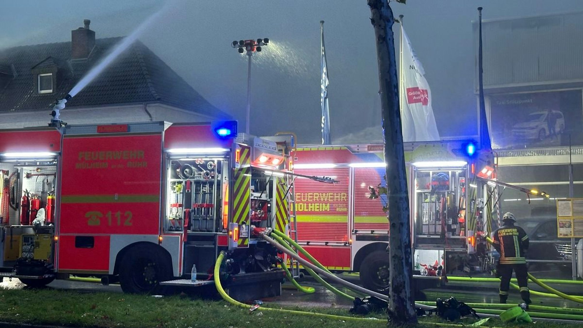 Feuerwehrfahrzeuge stehen vor einer verrauchten Halle in Mülheim.