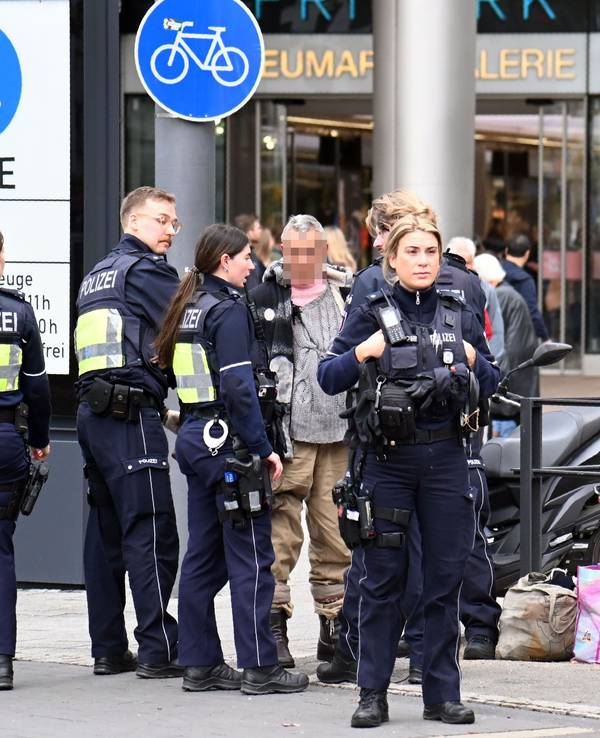 Mehrere Polizeikräfte stehen um einen älteren Mann herum.