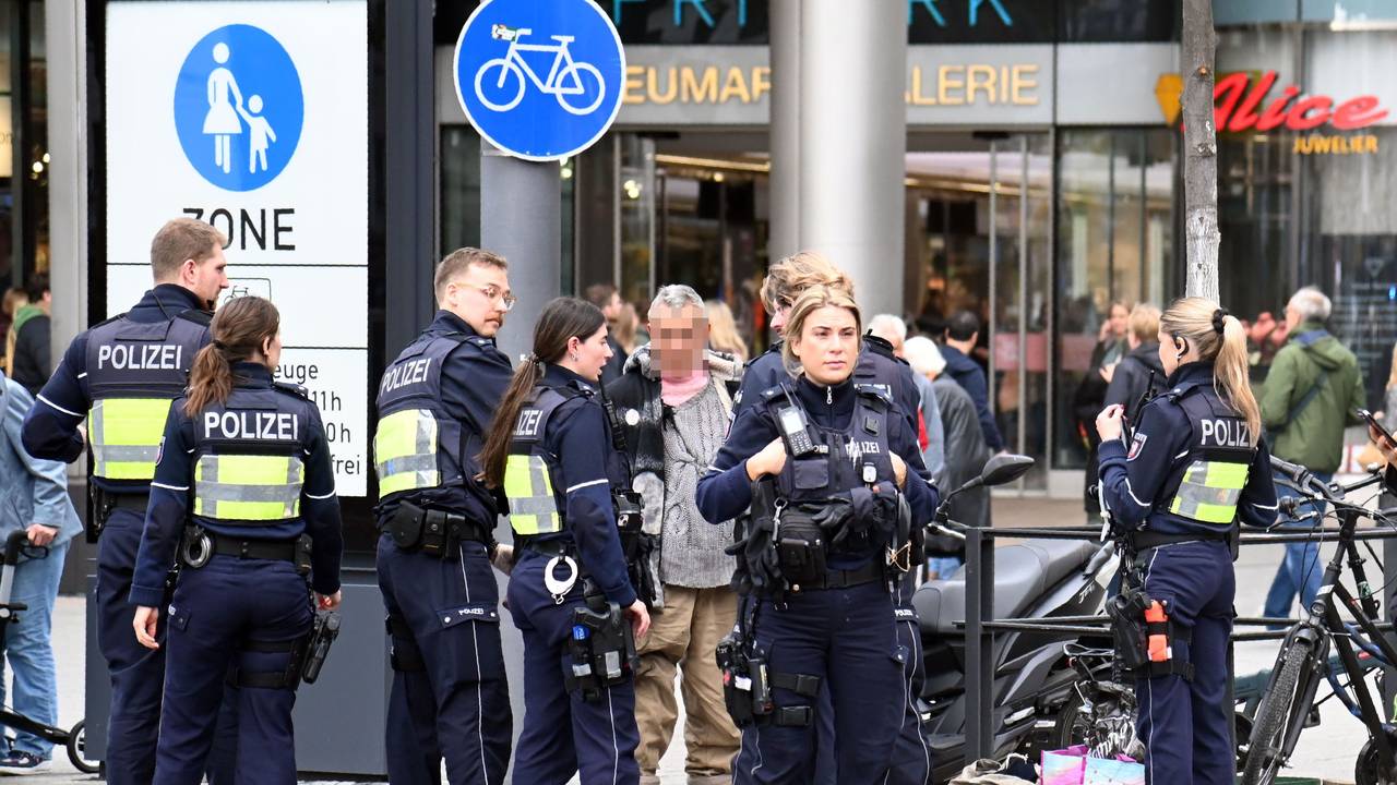 Mehrere Polizeikräfte stehen um einen älteren Mann herum.