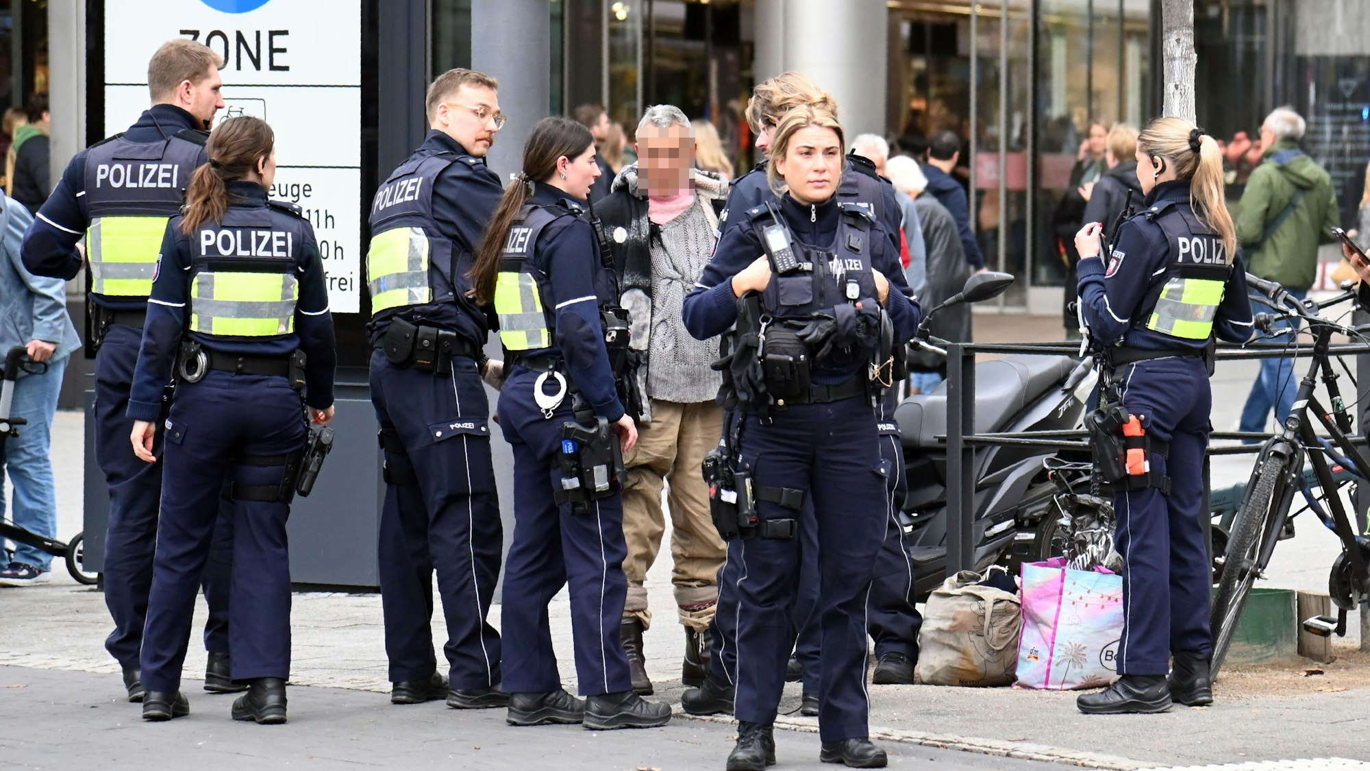 Mehrere Polizeikräfte stehen um einen älteren Mann herum.