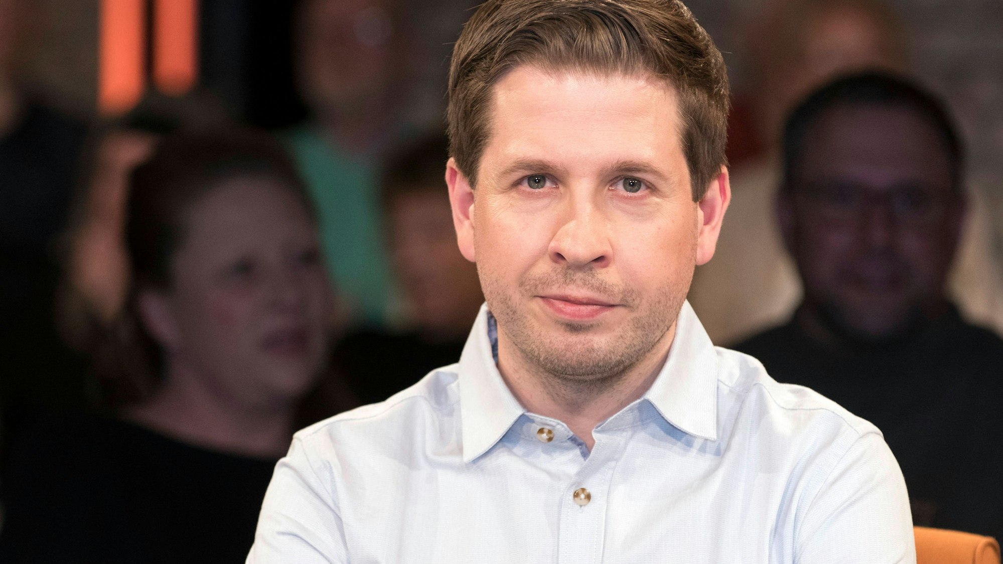 Kevin Kühnert schaut direkt in die Kamera, trägt ein hellblaues Hemd, unscharfer Hintergrund.