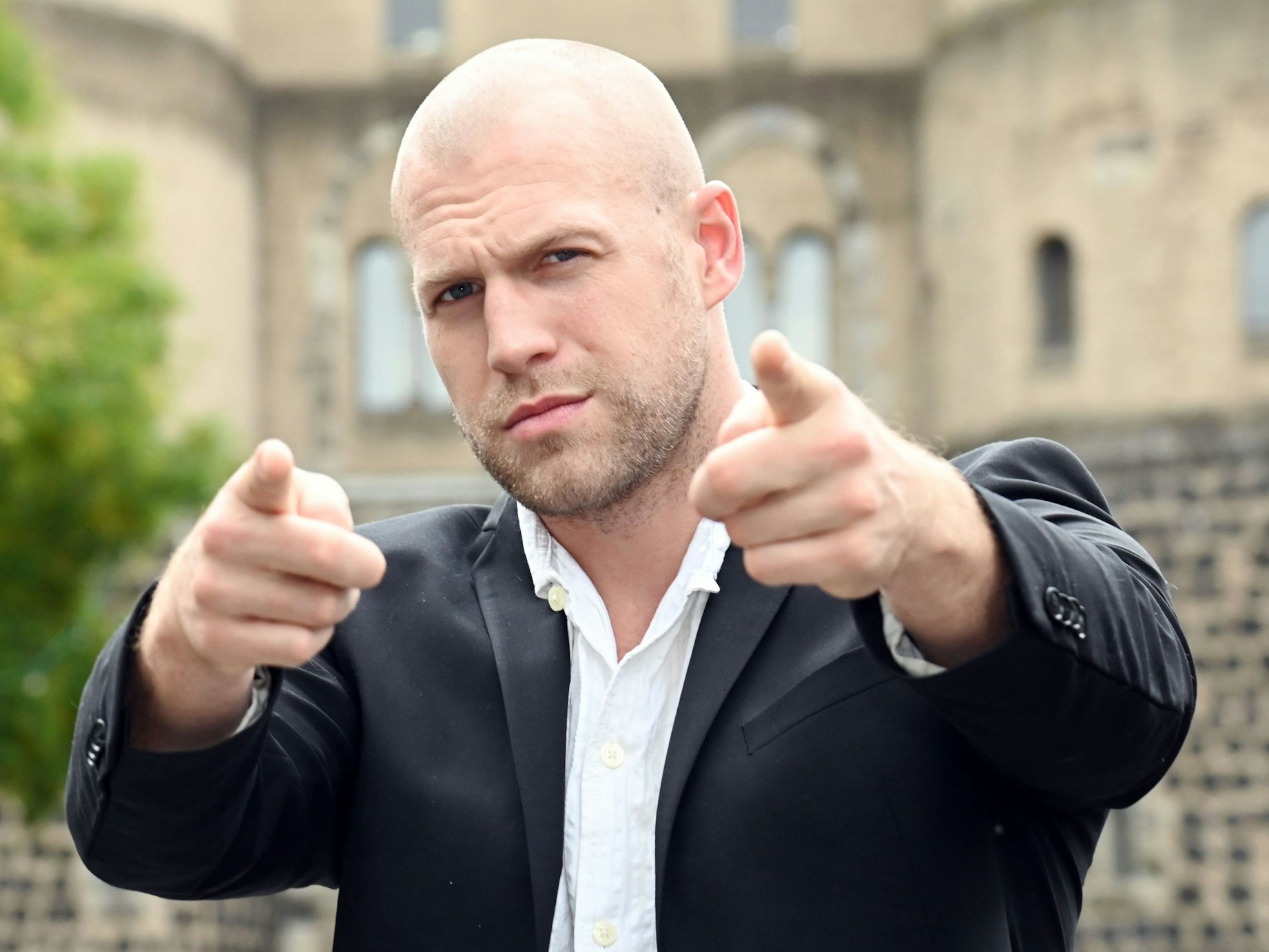 Lucas Weiss, Glatze, Dreitagebart, streckt die Arme nach vorne und legt die Stirn in Falten.