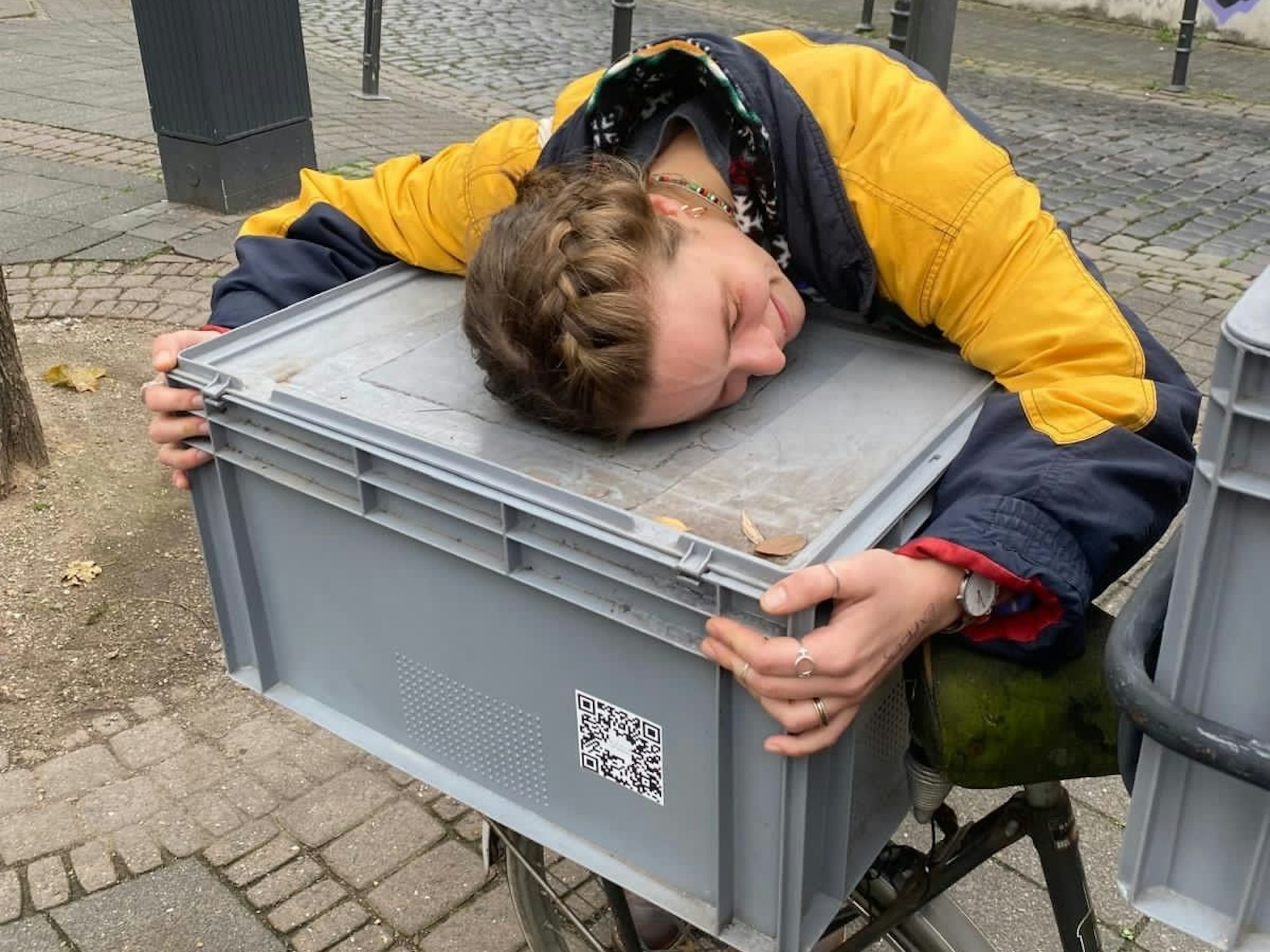 Eine Frau umarmt eine große Kiste, die auf einem Fahrrad steht.