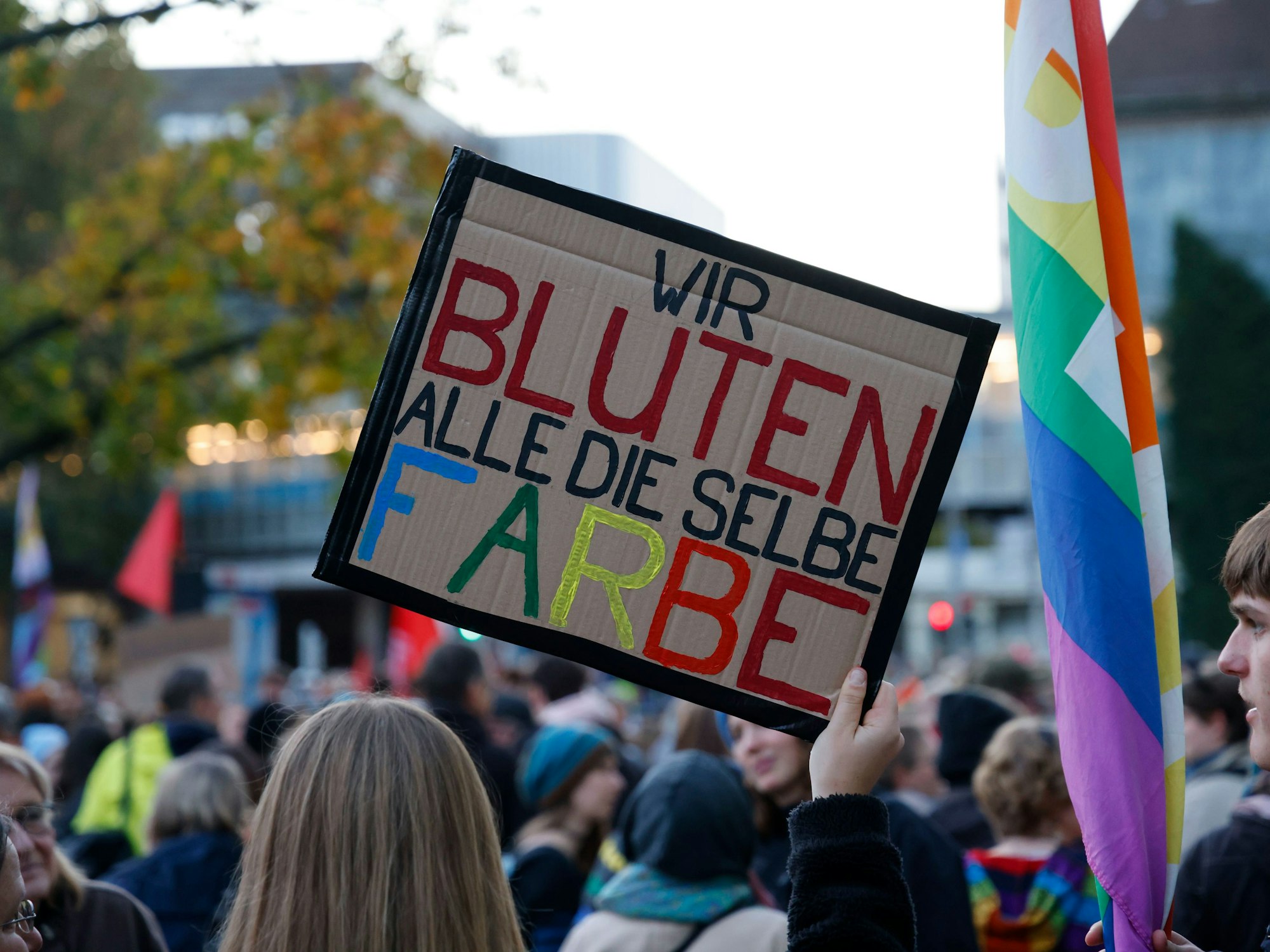 Bei einer Demonstration hält eine Frau ein Schild mit der Aufschrift „Wir bluten alle die selbe Farbe“ in die Höhe.