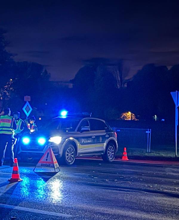 Einsatzkräfte der Polizei stehen an am Mittwochabend (22. Oktober 2025) in Erding an einer abgesperrten Straße.