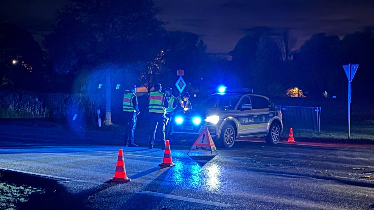 Einsatzkräfte der Polizei stehen an am Mittwochabend (22. Oktober 2025) in Erding an einer abgesperrten Straße.