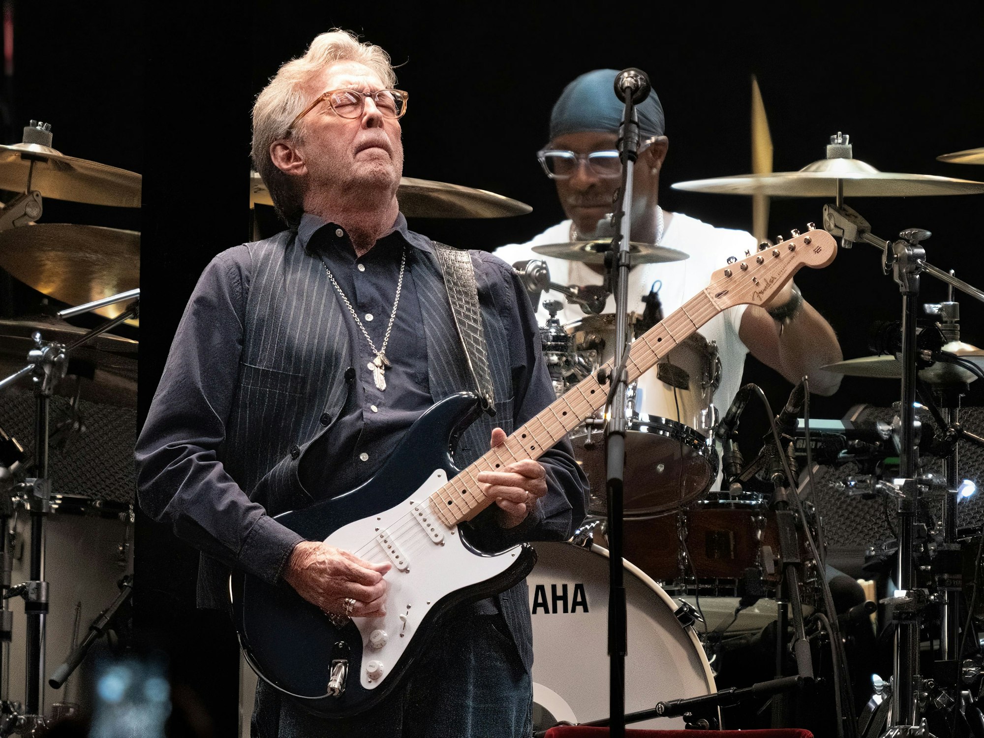 Eric Clapton spielt auf der Bühne Gitarre.