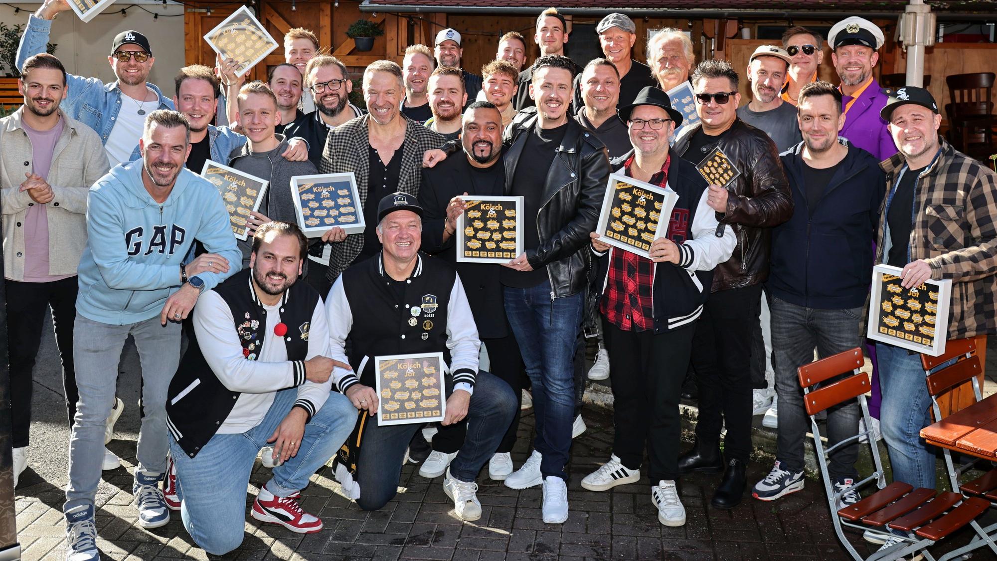 Viele Musiker halten Bilderrahmen von „Kölsch & Jot“ in der Hand.
