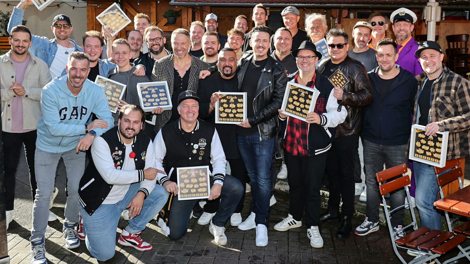 Viele Musiker halten Bilderrahmen von „Kölsch & Jot“ in der Hand.