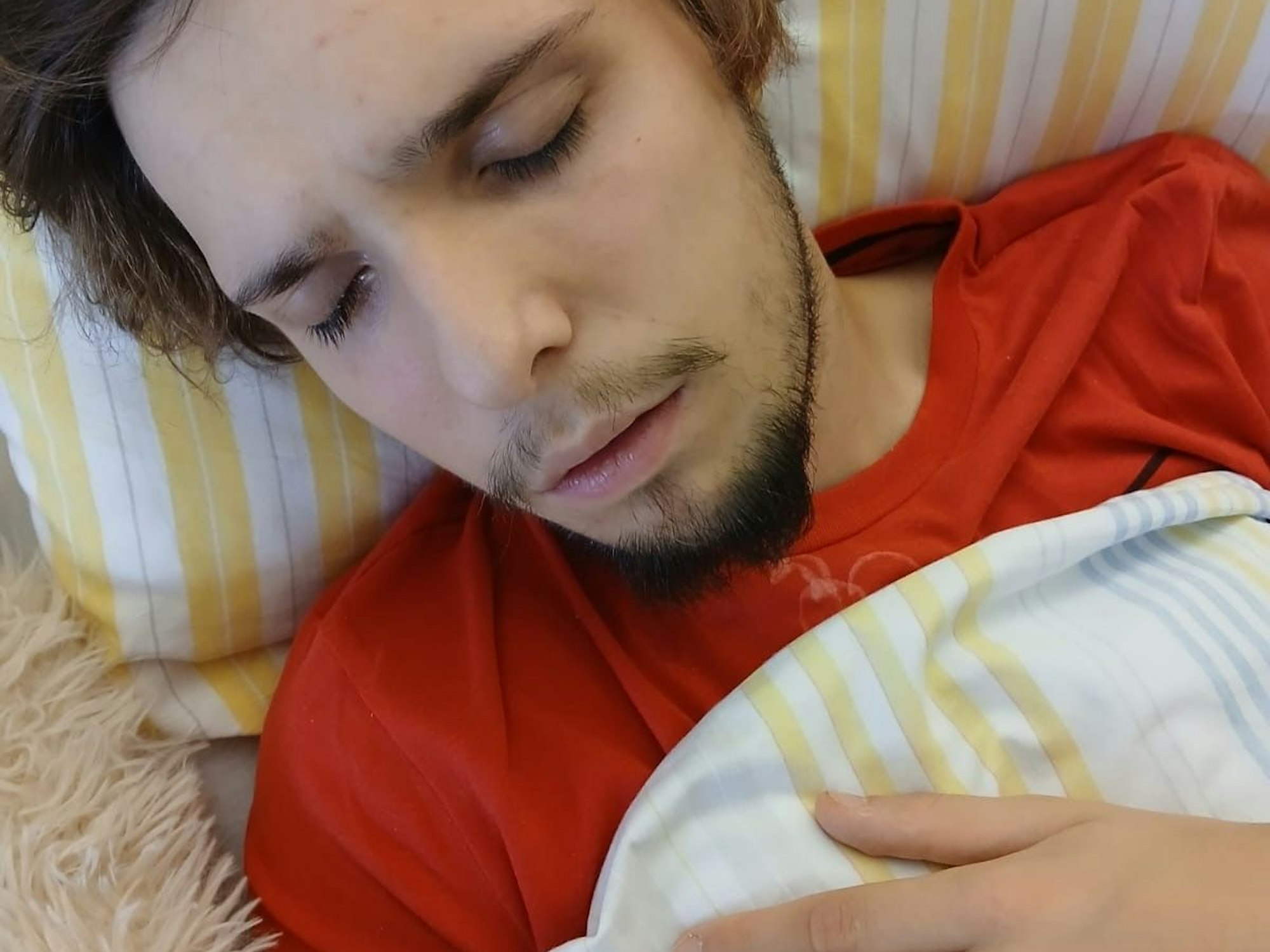 Ein junger Mann liegt mit geschlossenen Augen in einem Krankenhausbett.