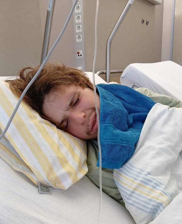 Ein junger Mann liegt in einem Krankenhausbett.