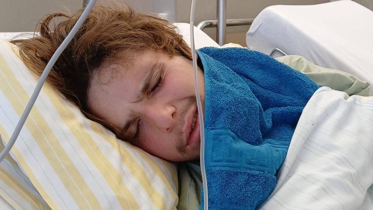 Ein junger Mann liegt in einem Krankenhausbett.
