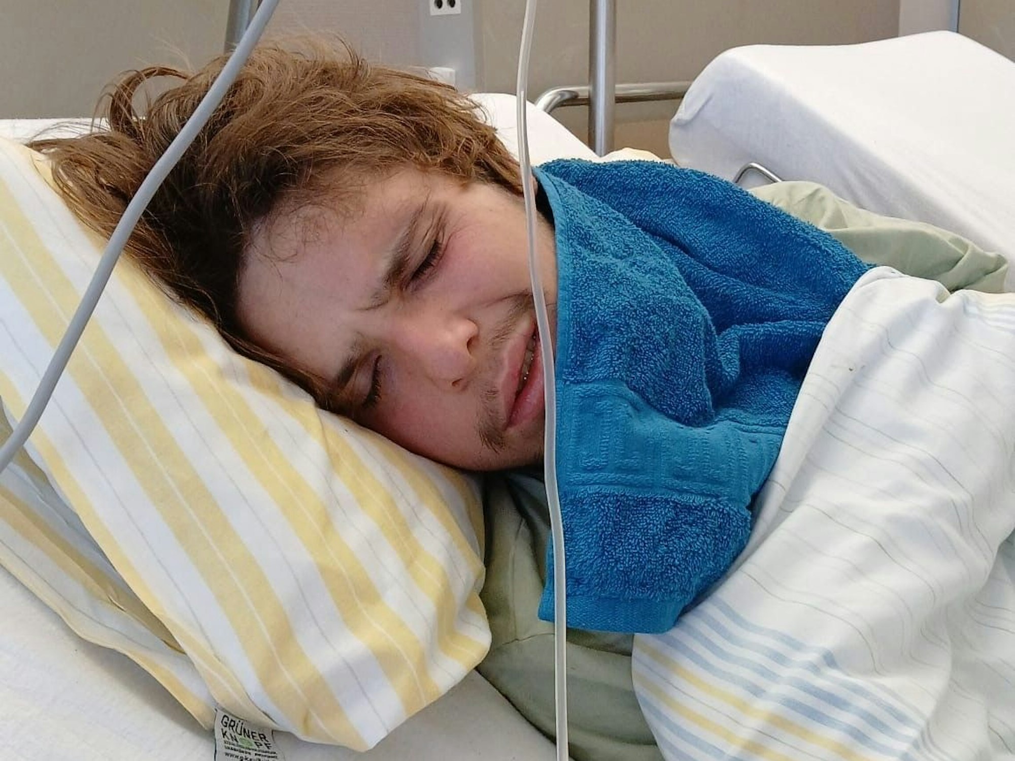 Ein junger Mann liegt in einem Krankenhausbett.