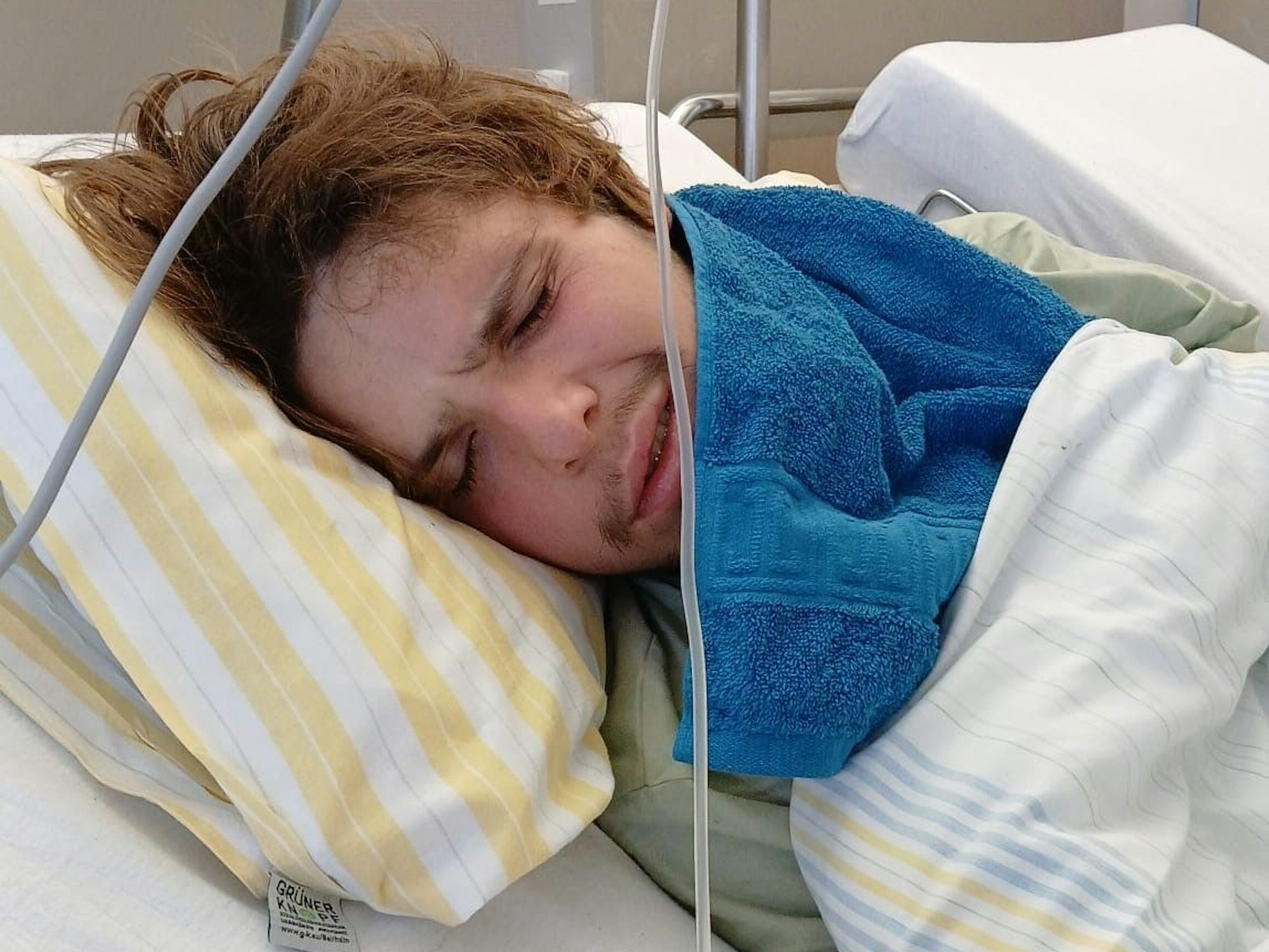 Ein junger Mann liegt in einem Krankenhausbett.