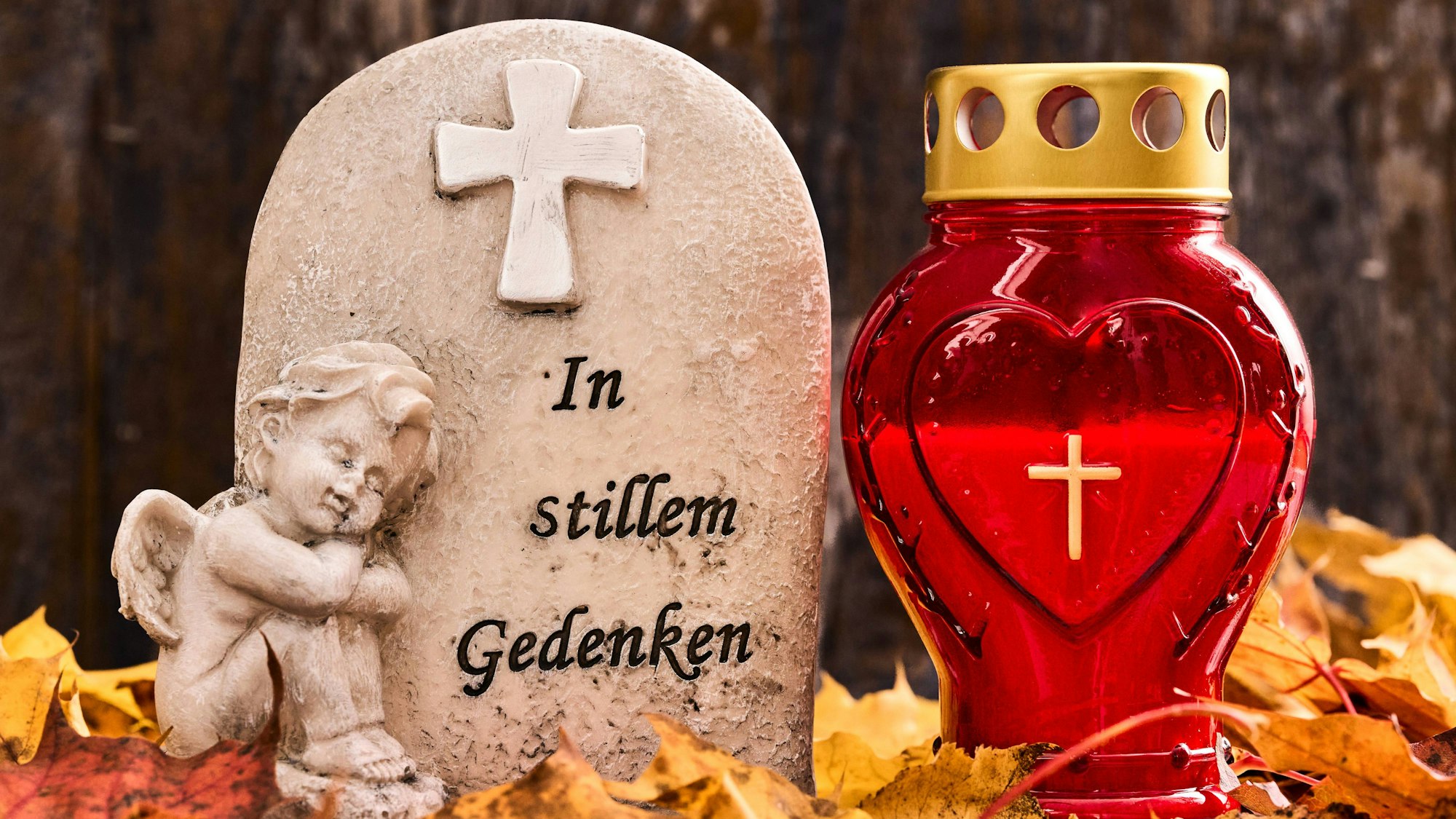 Bavaria, Germany - October 27, 2024: Gravestone with an angel and the inscription: In silent memory, next to a grave candle and autumn leaves. Symbolic image of grief and loss *** Grabstein mit einem Engel und dem Schriftzug: In stillem Gedenken, neben einer Grabkerze und Herbstlaub. Symbolbild Trauer und Verlust