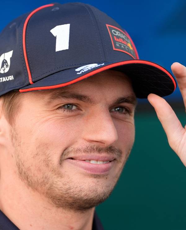 Max Verstappen fasst sich an die Kappe und lächelt.