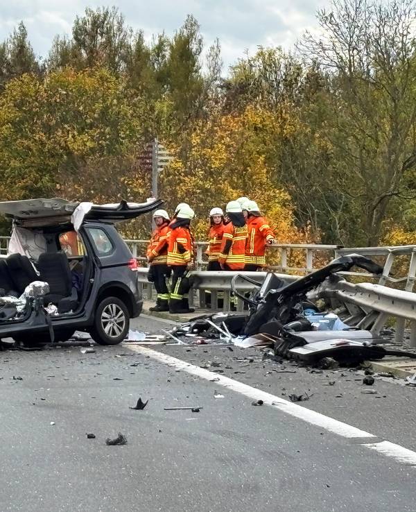 Einsatzkräfte der Feuerwehr stehen an der Unfallstelle auf der Bundesstraße 4 auf einer Brücke über den Mittellandkanal neben einem zerstörten Fahrzeug.