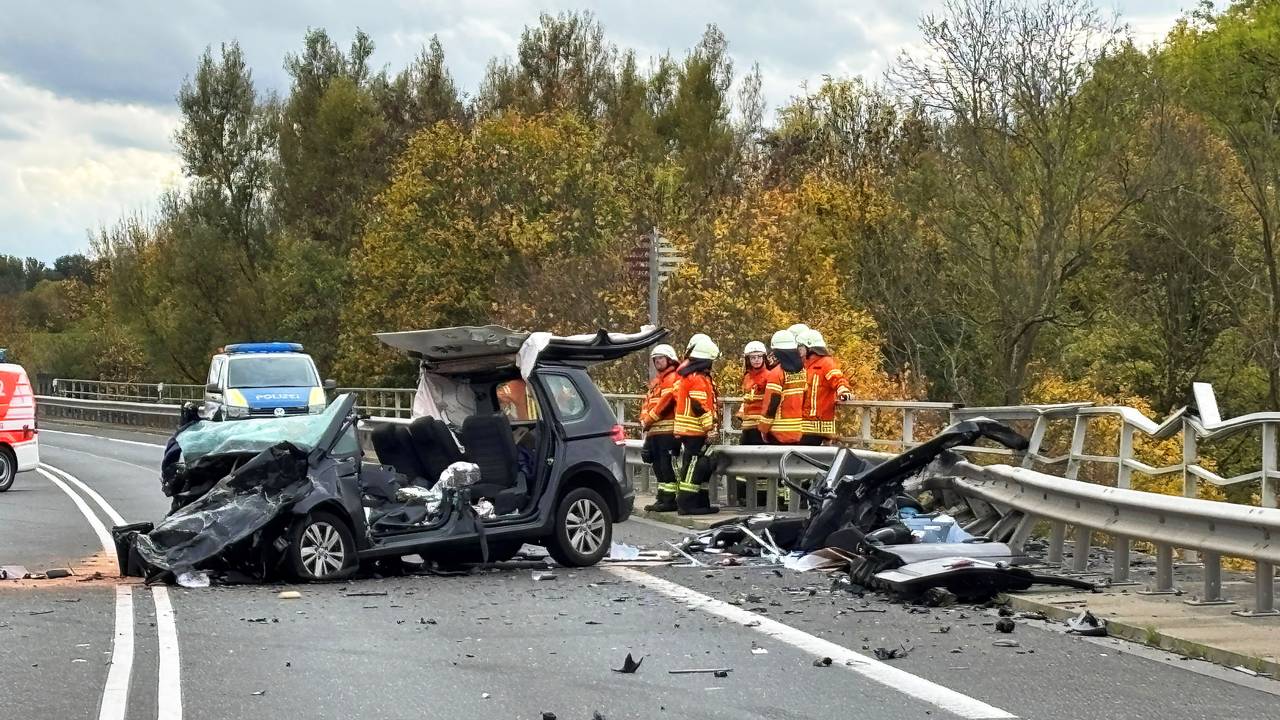 Einsatzkräfte der Feuerwehr stehen an der Unfallstelle auf der Bundesstraße 4 auf einer Brücke über den Mittellandkanal neben einem zerstörten Fahrzeug.