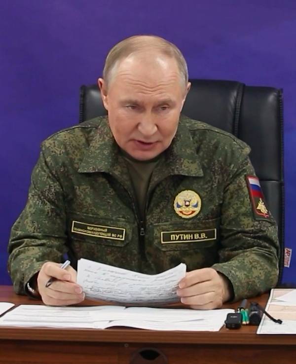 Wladimir Putin trägt eine Uniform und verliest ein Dokument.