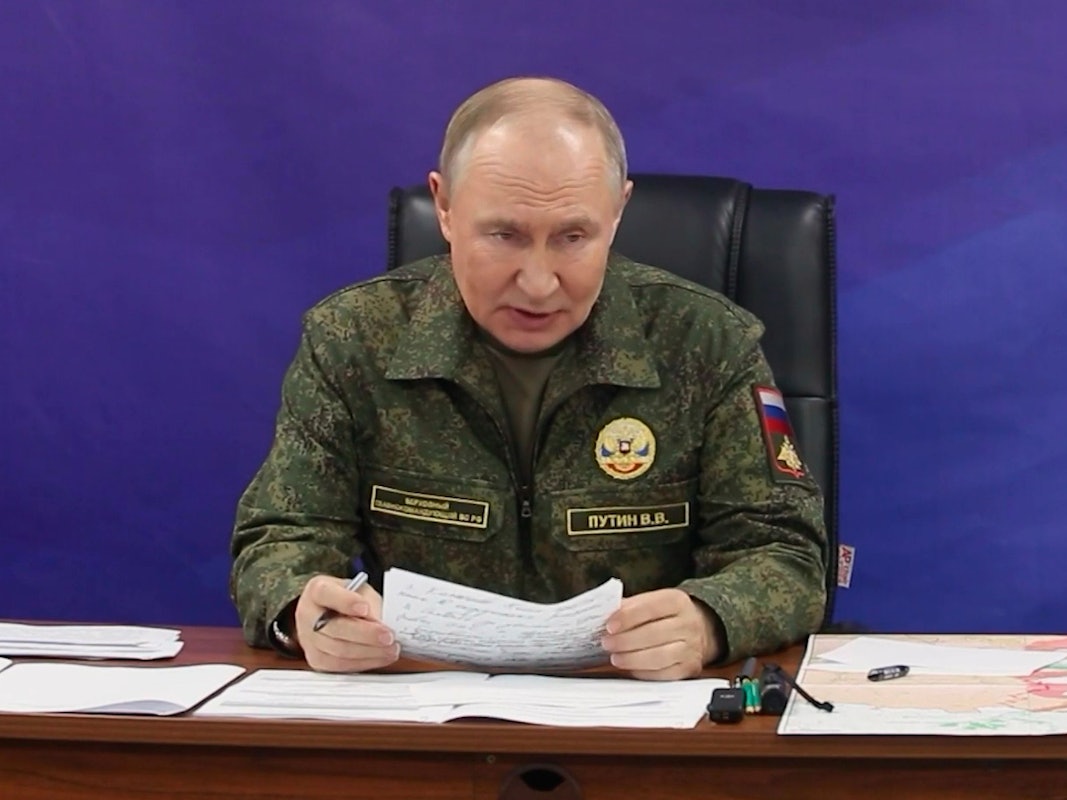 Wladimir Putin trägt eine Uniform und verliest ein Dokument.