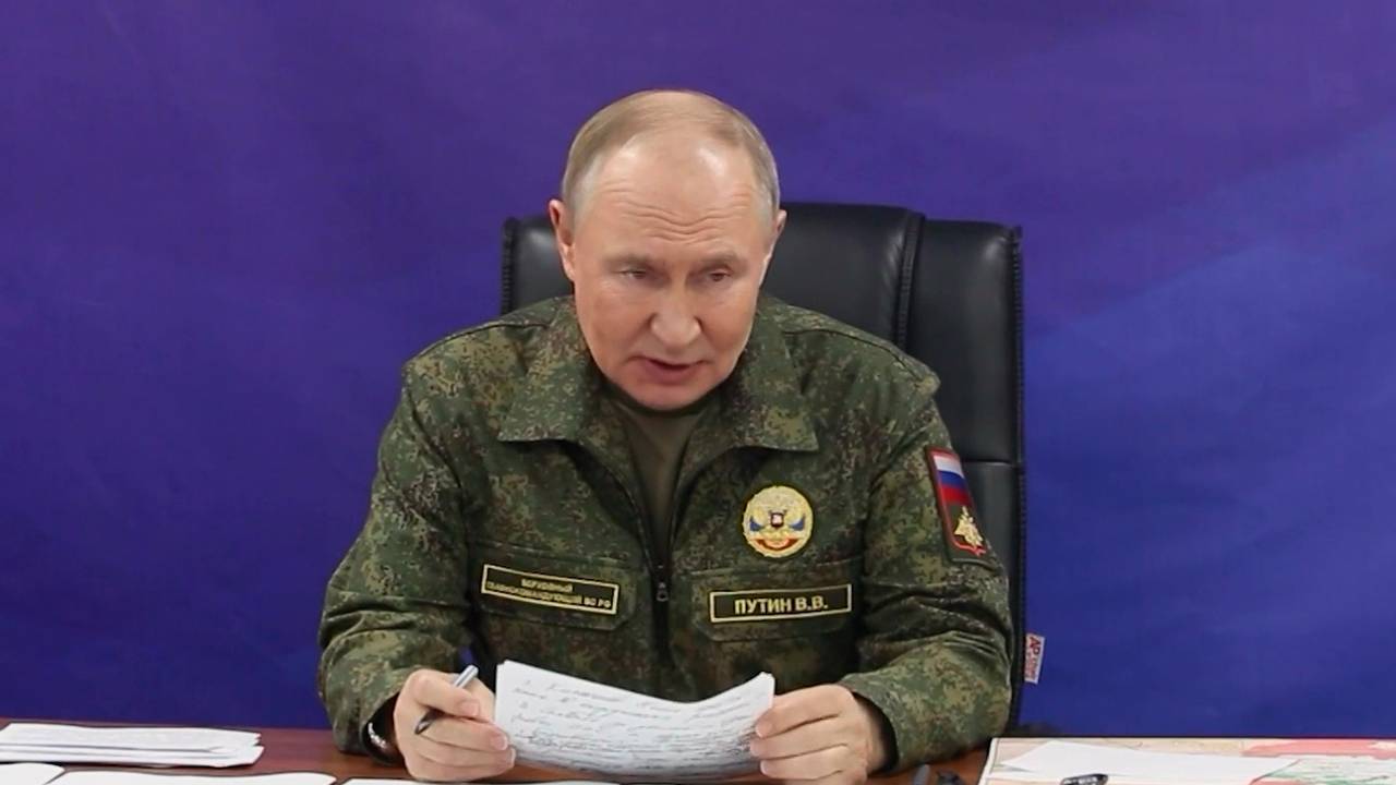 Wladimir Putin trägt eine Uniform und verliest ein Dokument.