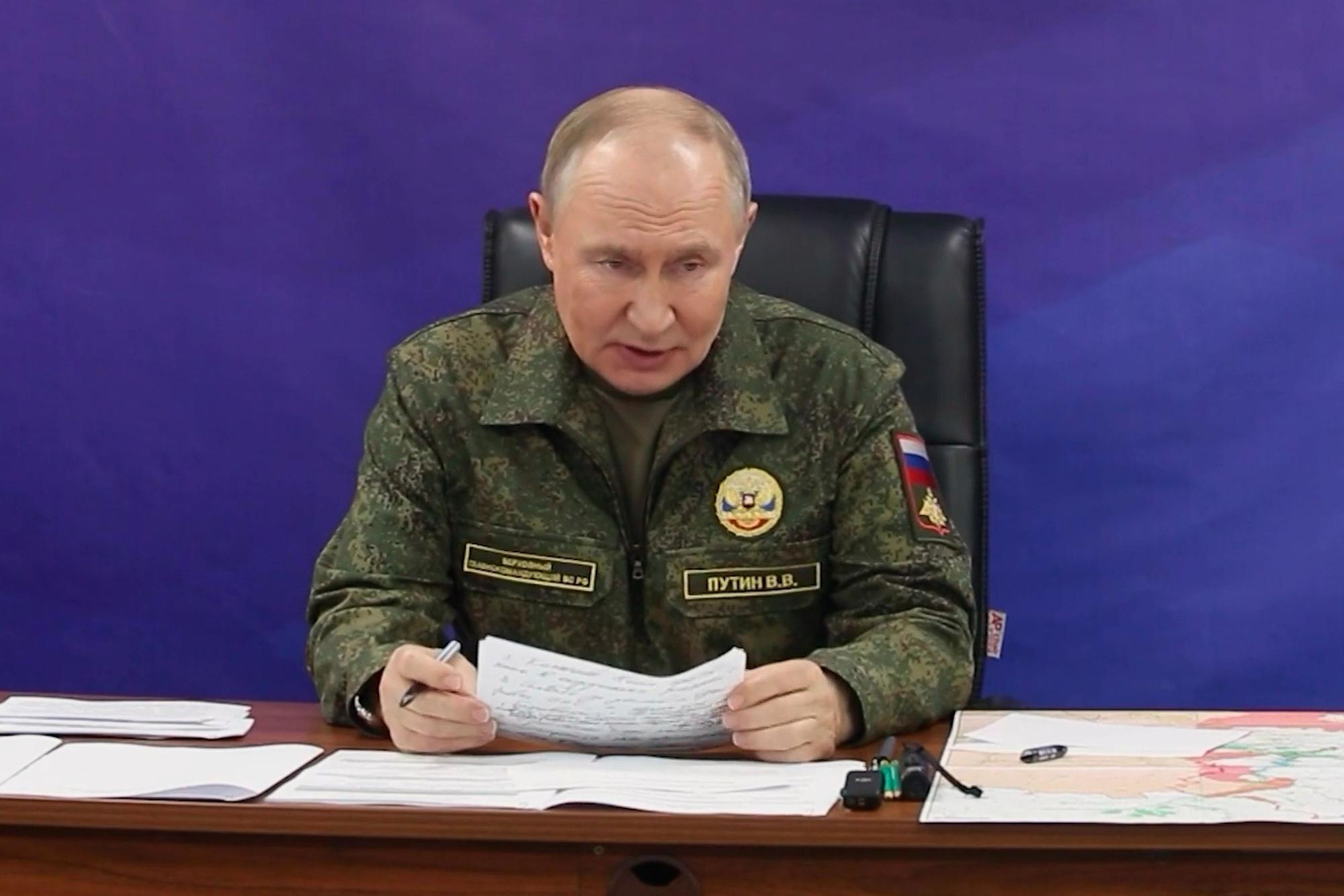 Wladimir Putin trägt eine Uniform und verliest ein Dokument.