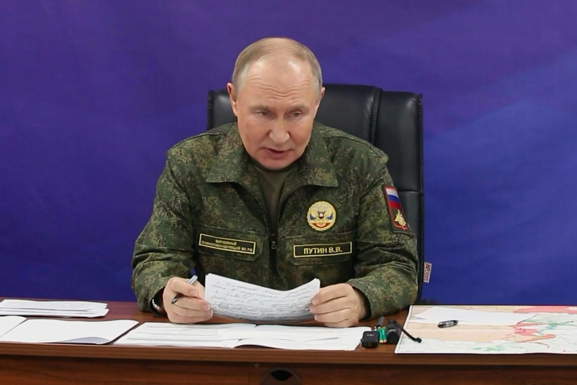 Wladimir Putin trägt eine Uniform und verliest ein Dokument.