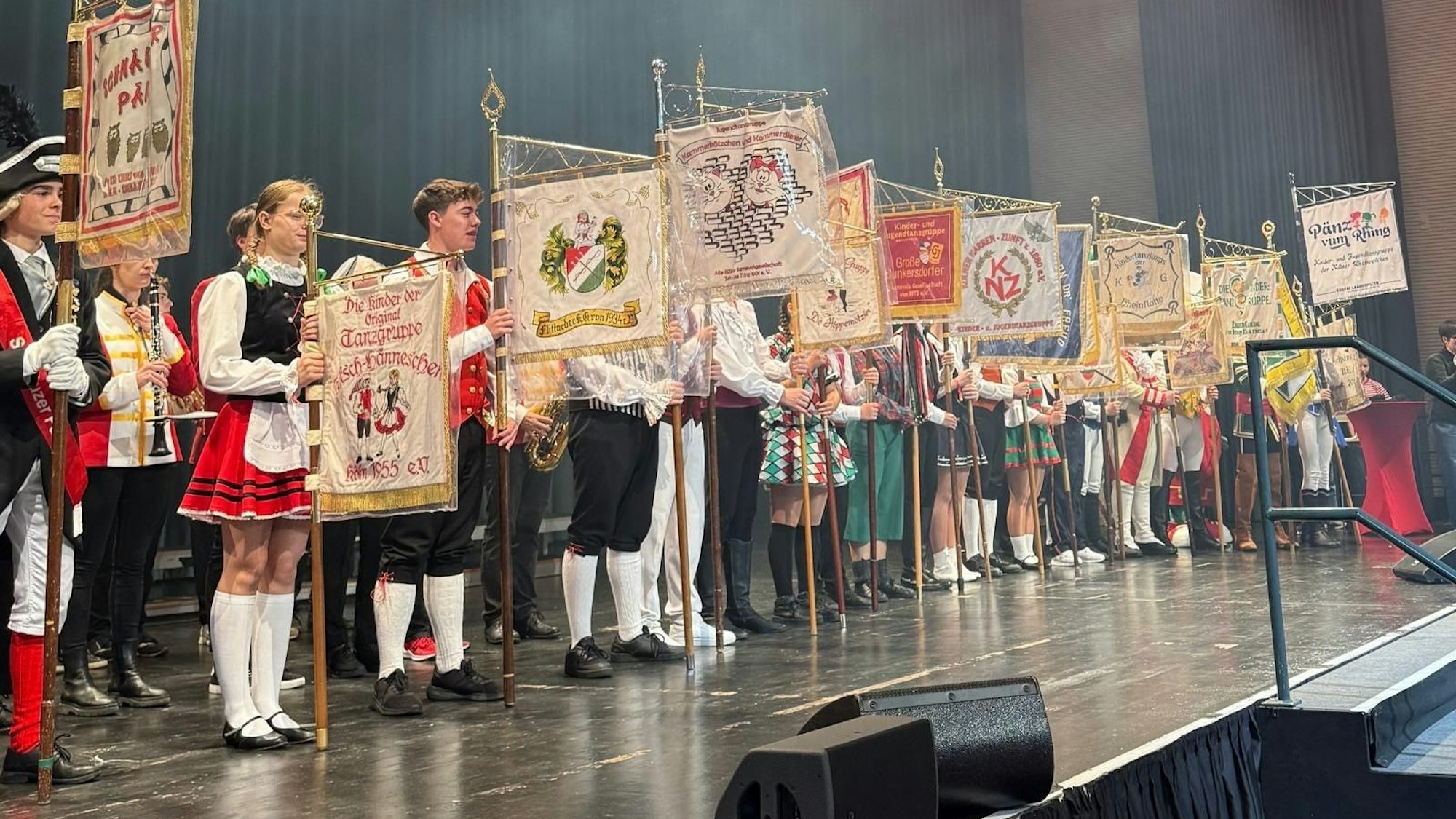Jugendliche stehen mit ihren Plaggen auf der Bühne.