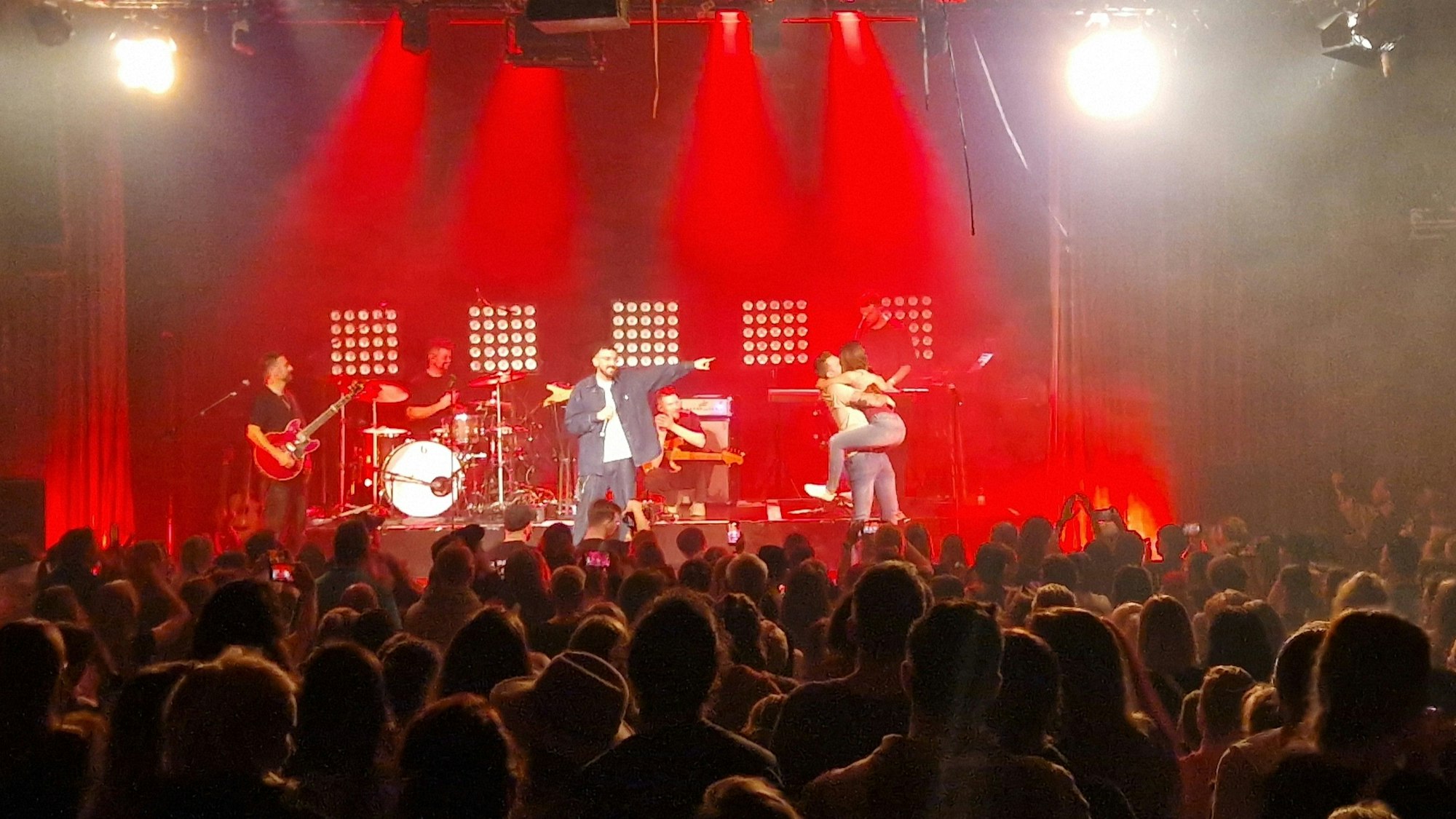 Nico Gomez bei einem Konzert in Köln mit einem Pärchen auf der Bühne.