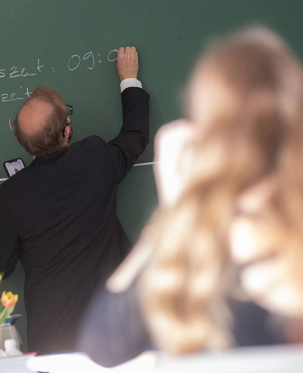 Ein Lehrer schreibt an der Singbergschule am ersten Tag der schriftlichen Abiturprüfungen 2022 in Hessen die Anfangszeit des Deutsch-Abiturs auf die Tafel.