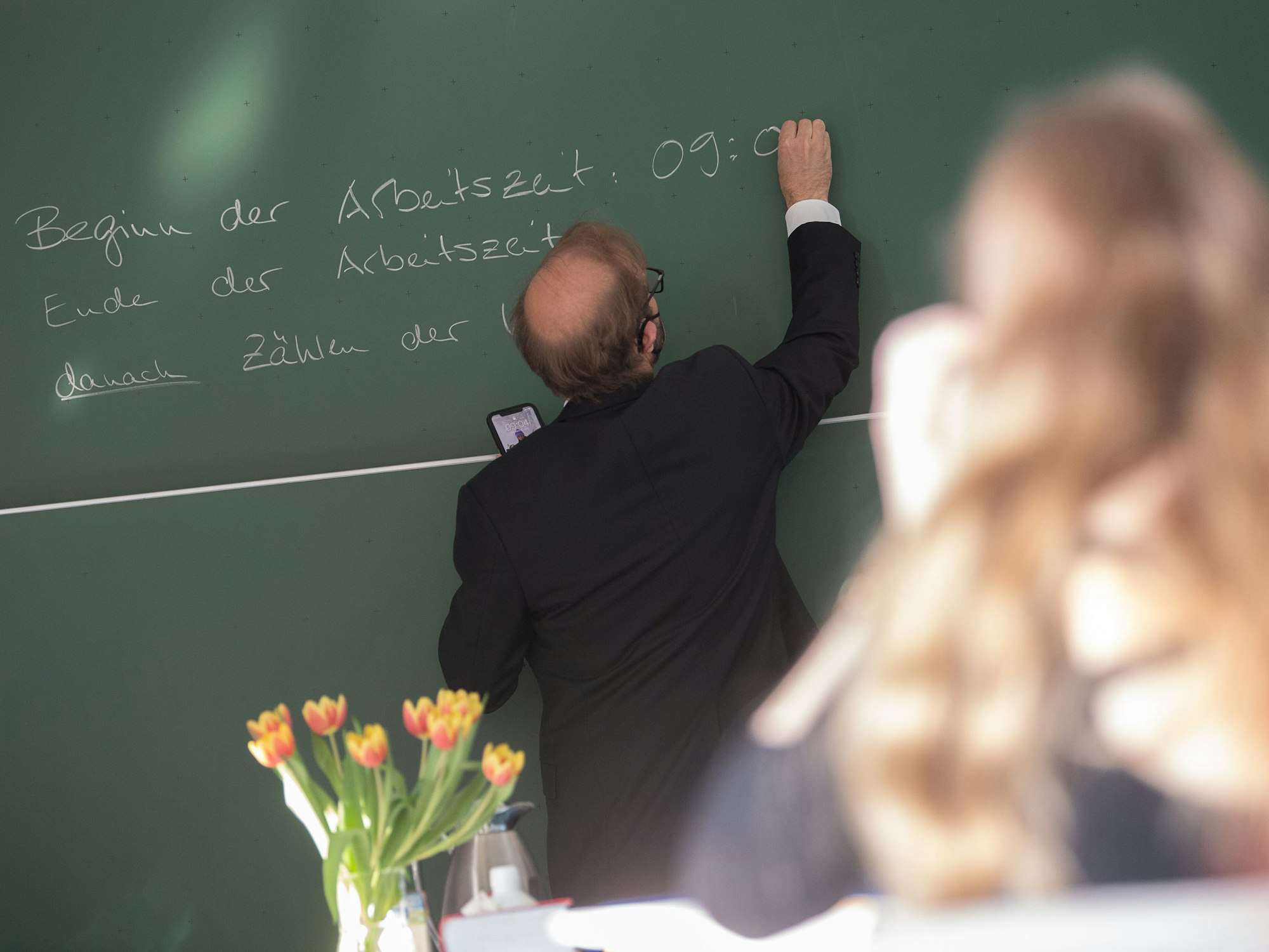 Ein Lehrer schreibt an der Singbergschule am ersten Tag der schriftlichen Abiturprüfungen 2022 in Hessen die Anfangszeit des Deutsch-Abiturs auf die Tafel.