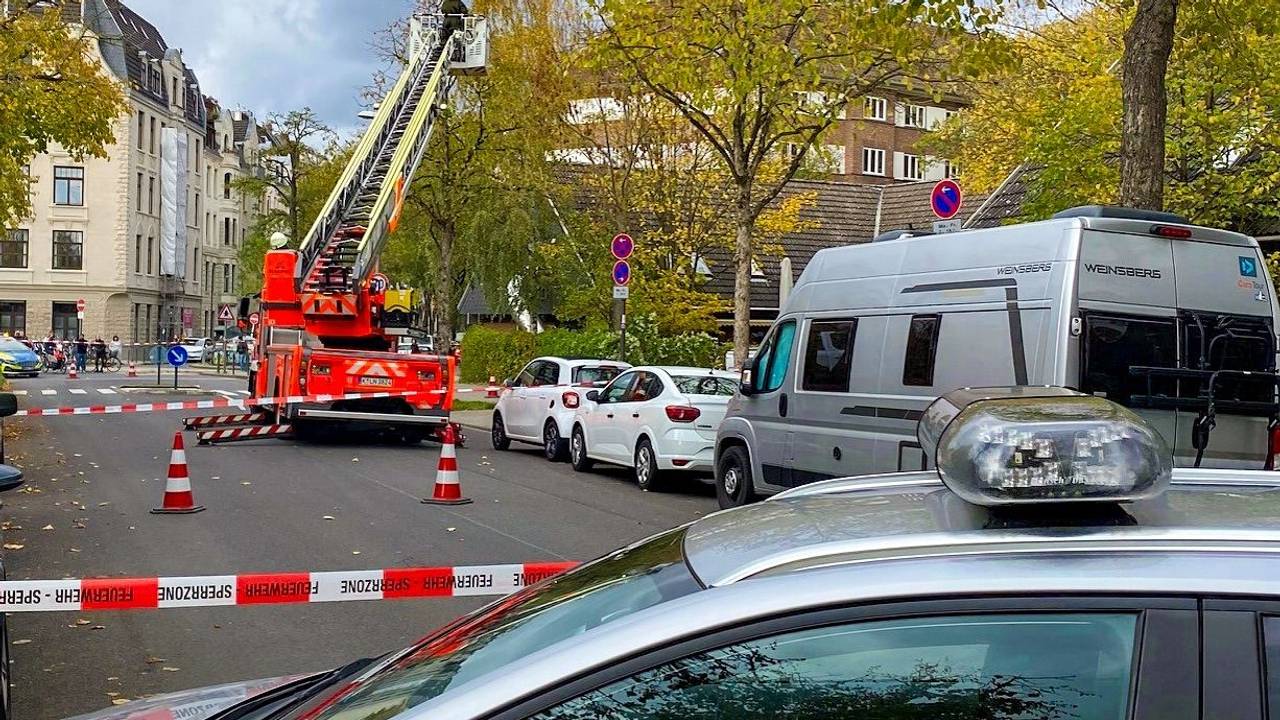 Ein Mann steht im Korb einer Drehleiter, die an einen Straßenbaum heranreicht. Die Straße ist mit Flatterband abgesperrt.