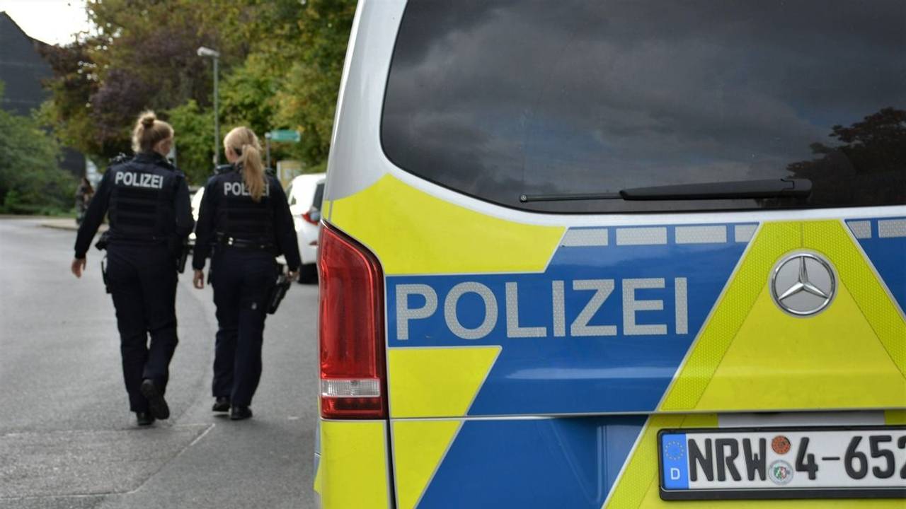 Zwei Polizistinnen laufen an einem Polizeifahrzeug entlang.