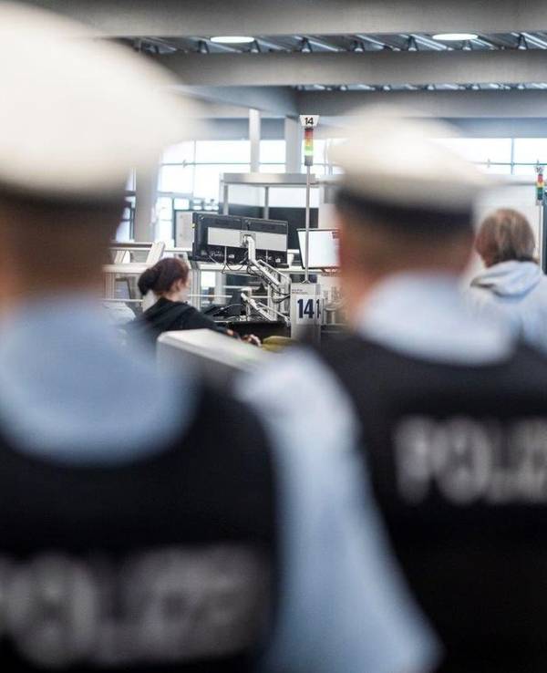 Zwei Bundespolizisten stehen an der Sicherheitskontrolle eines Flughafens.