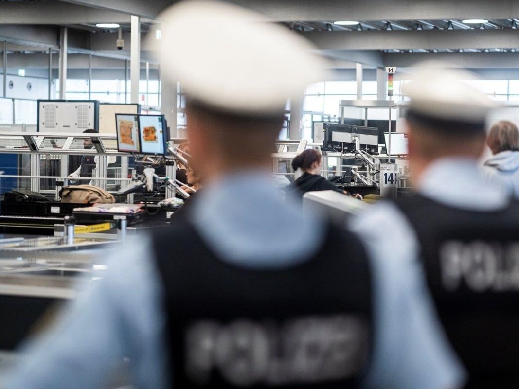 Zwei Bundespolizisten stehen an der Sicherheitskontrolle eines Flughafens.