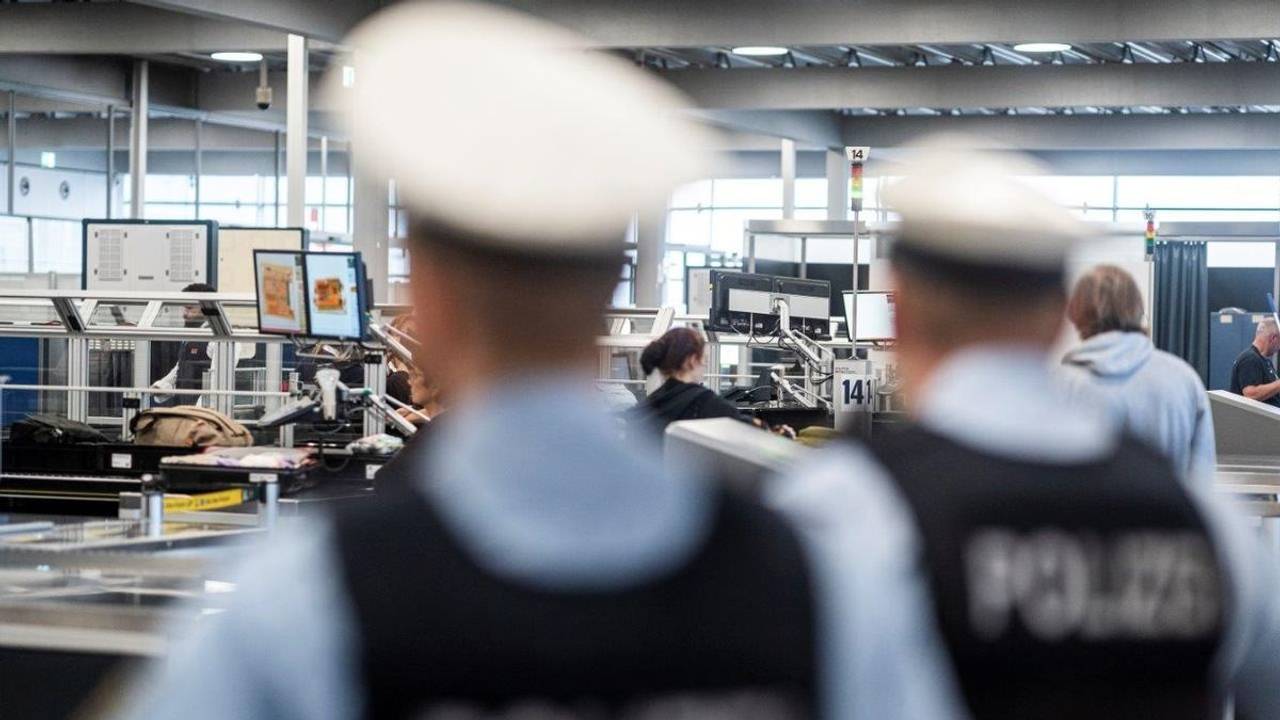 Zwei Bundespolizisten stehen an der Sicherheitskontrolle eines Flughafens.