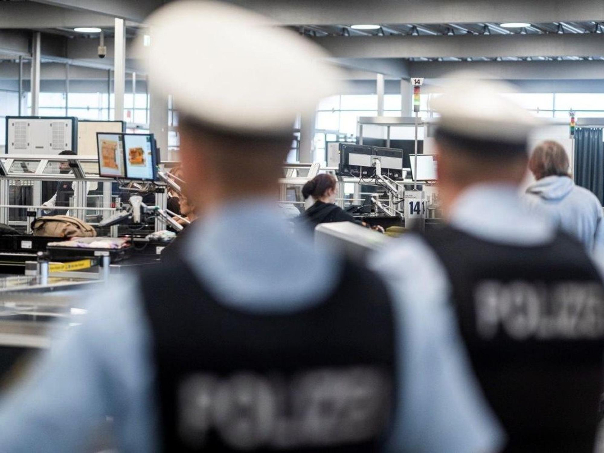 Zwei Bundespolizisten stehen an der Sicherheitskontrolle eines Flughafens.