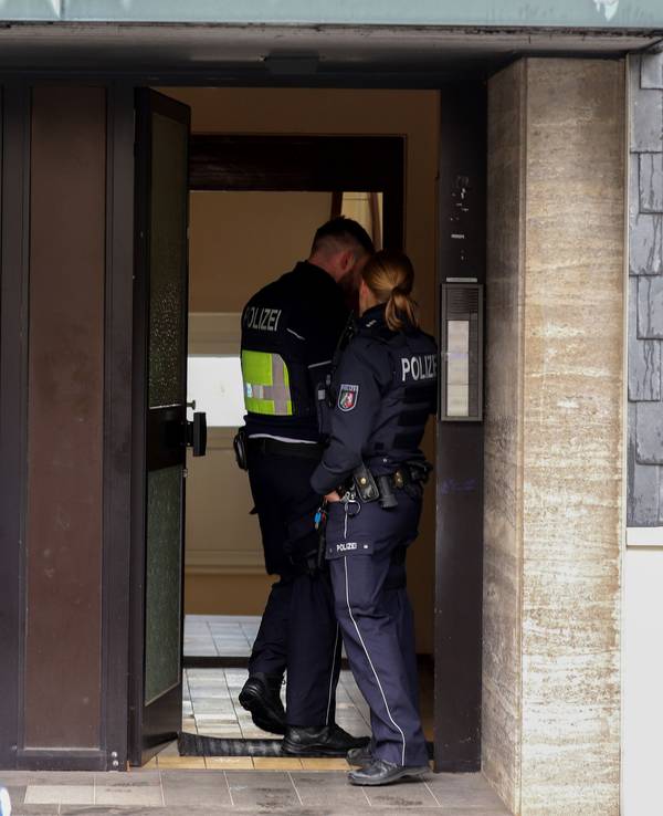 Polizisten stehen im Hauseingang eines Gebäudes, das im Zusammenhang mit einer Razzia gegen organisierte Kriminalität steht. Bei dem Einsatz hat es nach Angaben der Staatsanwaltschaft mehrere Waffenfunde gegeben.