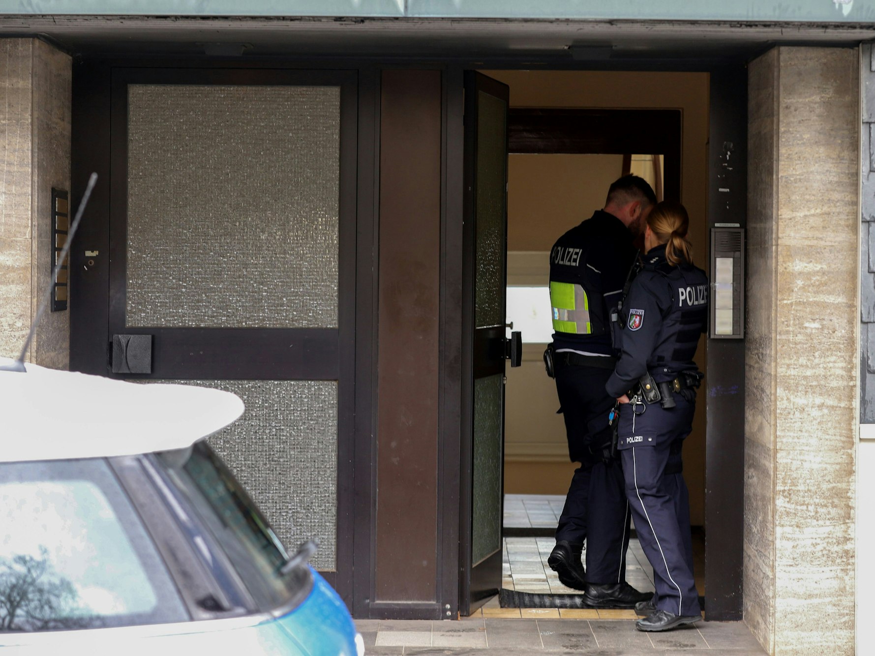 Polizisten stehen im Hauseingang eines Gebäudes, das im Zusammenhang mit einer Razzia gegen organisierte Kriminalität steht. Bei dem Einsatz hat es nach Angaben der Staatsanwaltschaft mehrere Waffenfunde gegeben.