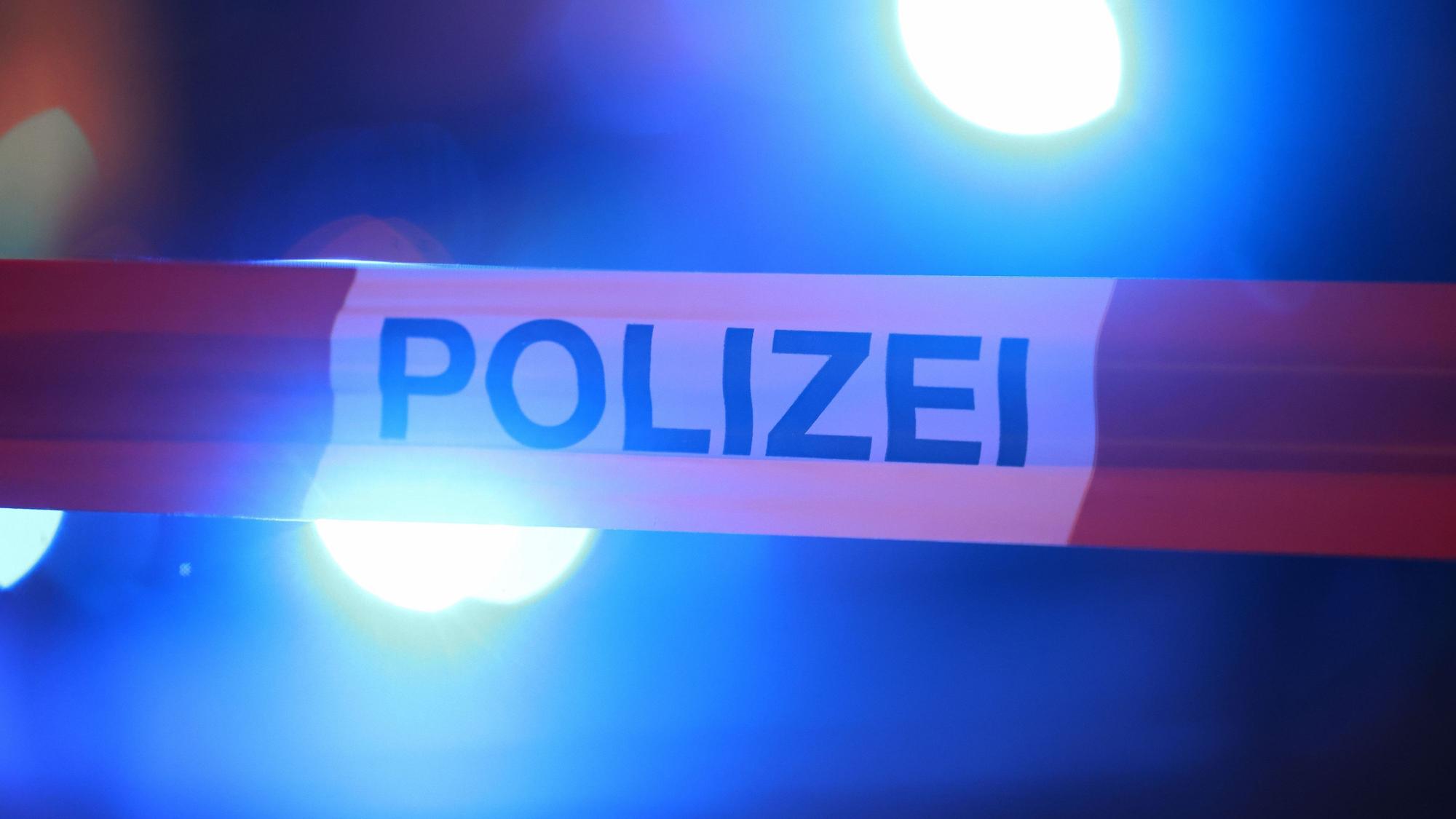 Blaulichter leuchten hinter einem Absperrband der Polizei.
