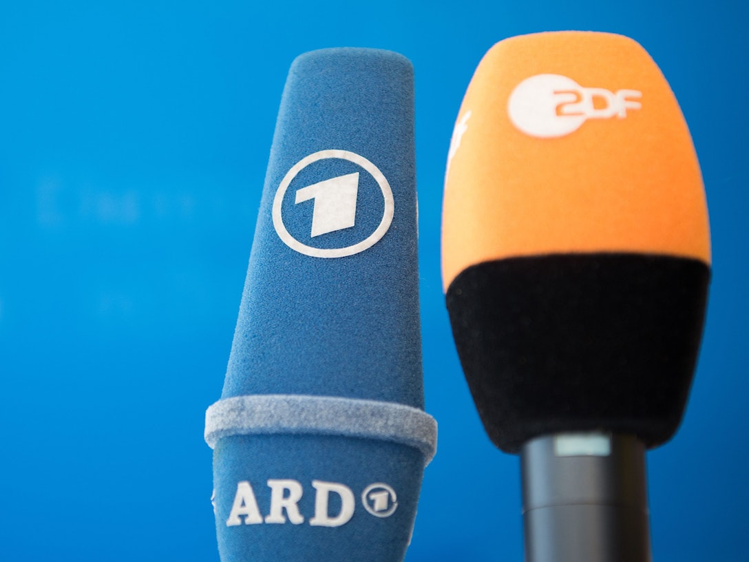 Die Mikrofone von ARD und ZDF sind vor einer Pressekonferenz nebeneinander aufgestellt.