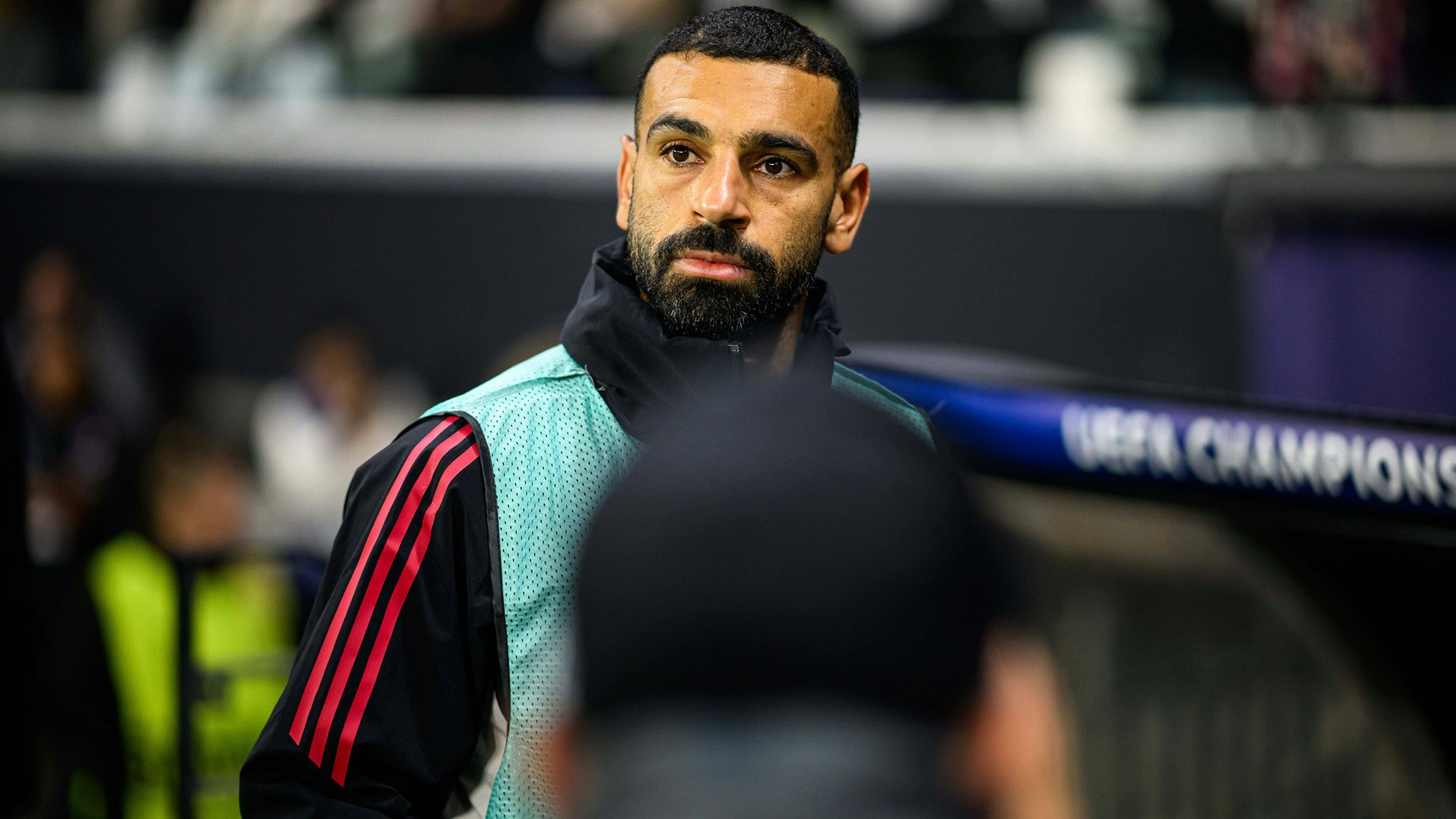 Mohamed Salah blickt konzentriert von der Seitenlinie bei einem Champions-League-Spiel.