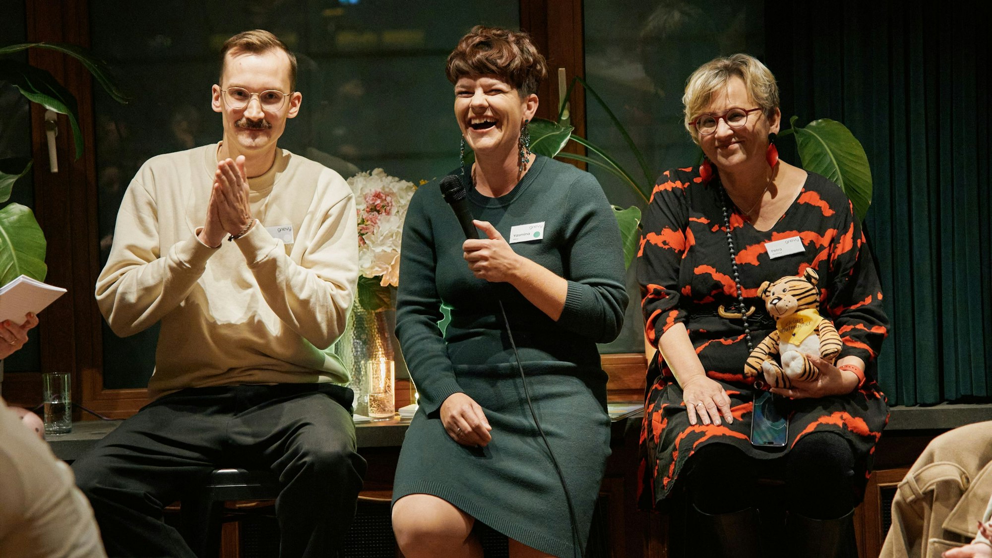 Tobi, Yasmina und Petra sitzen auf Stühlen und erzählen dem Publikum etwas.